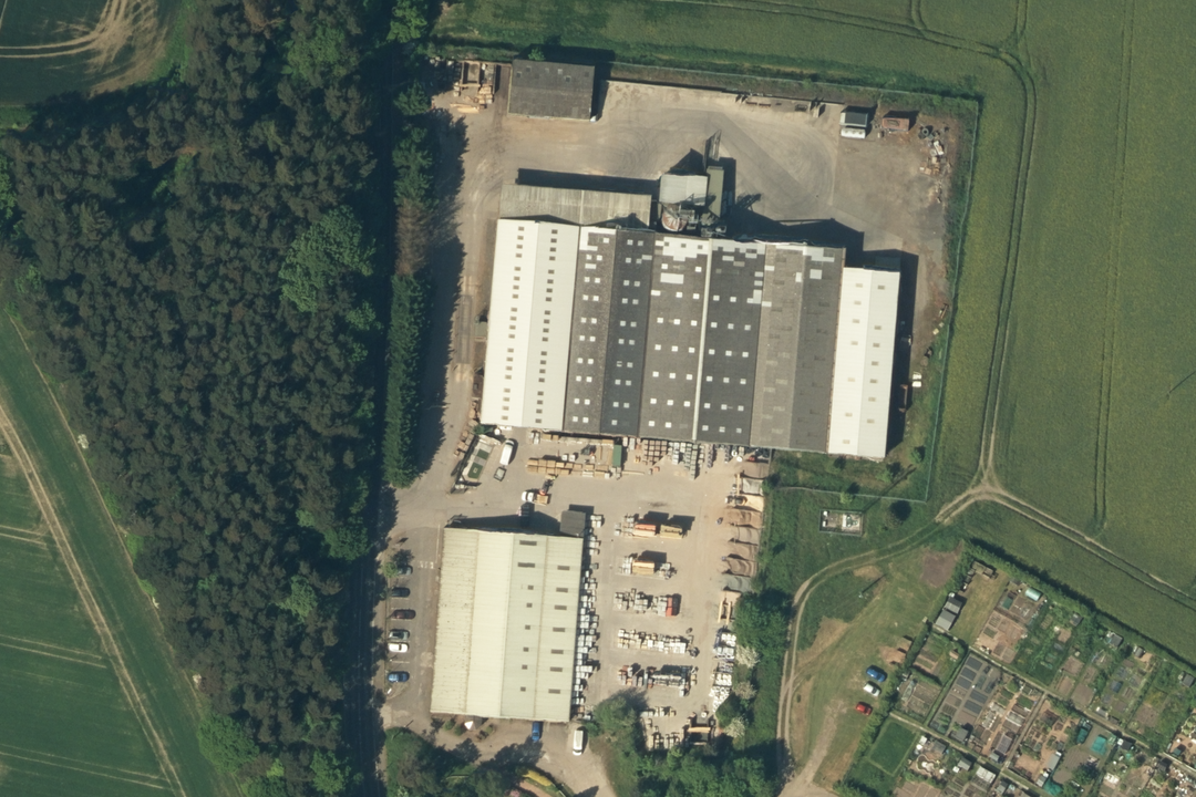 OS aerial imagery section of an industrial site with warehouse buildings, loading yards and access roads set in open farmland