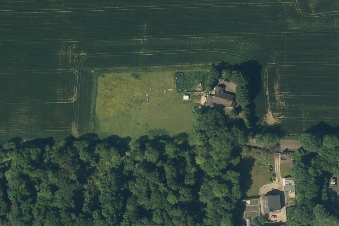OS aerial imagery section showing an isolated rural farmstead with outbuildings, garden and surrounding arable and woodland