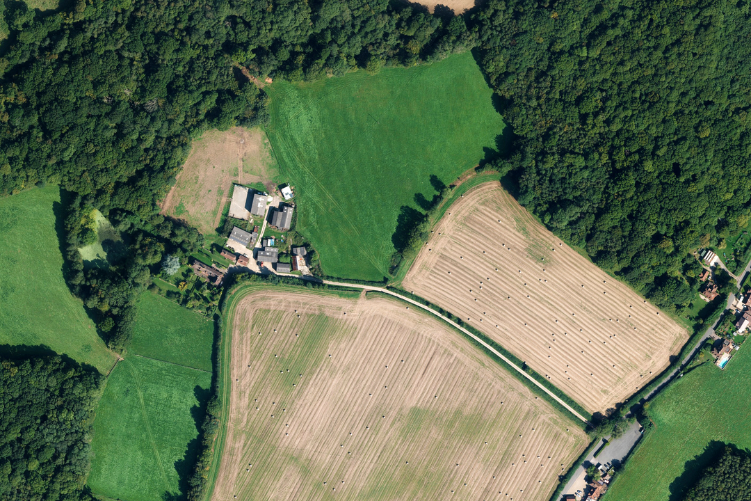 OS aerial imagery section of a farm complex surrounded by arable fields and deciduous woodland in a rural landscape